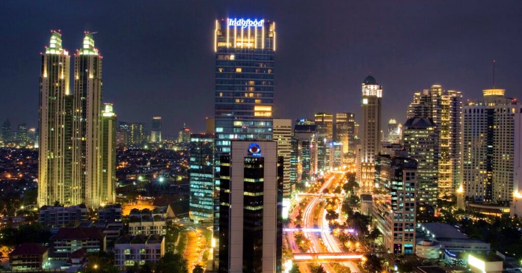 A stunning aerial view of Jakarta's illuminated skyline at night, showcasing tall skyscrapers and busy traffic.