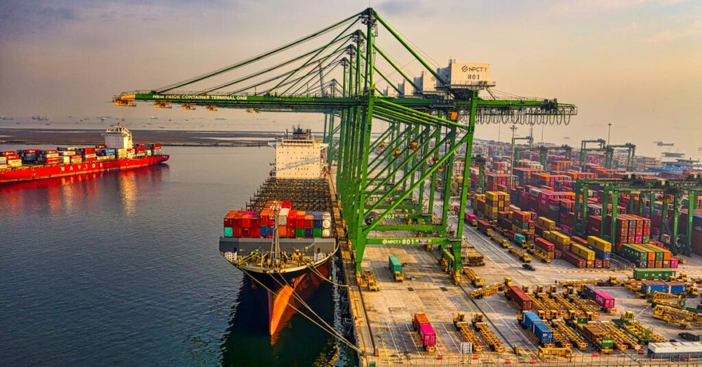 A bustling aerial view of a container port in North Jakarta, Indonesia with ships and cranes.